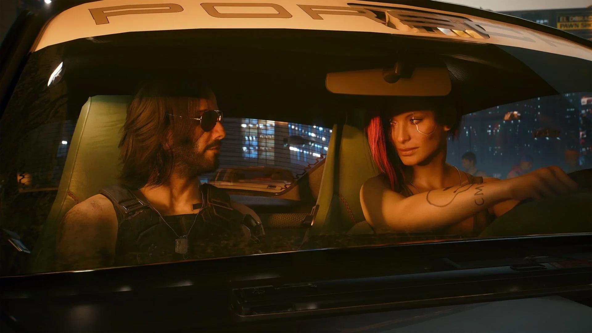 V drives a Porsche through Night City at night with Johnny Silverhand, in aviator sunglasses, in the passenger seat in Cyberpunk 2077.
