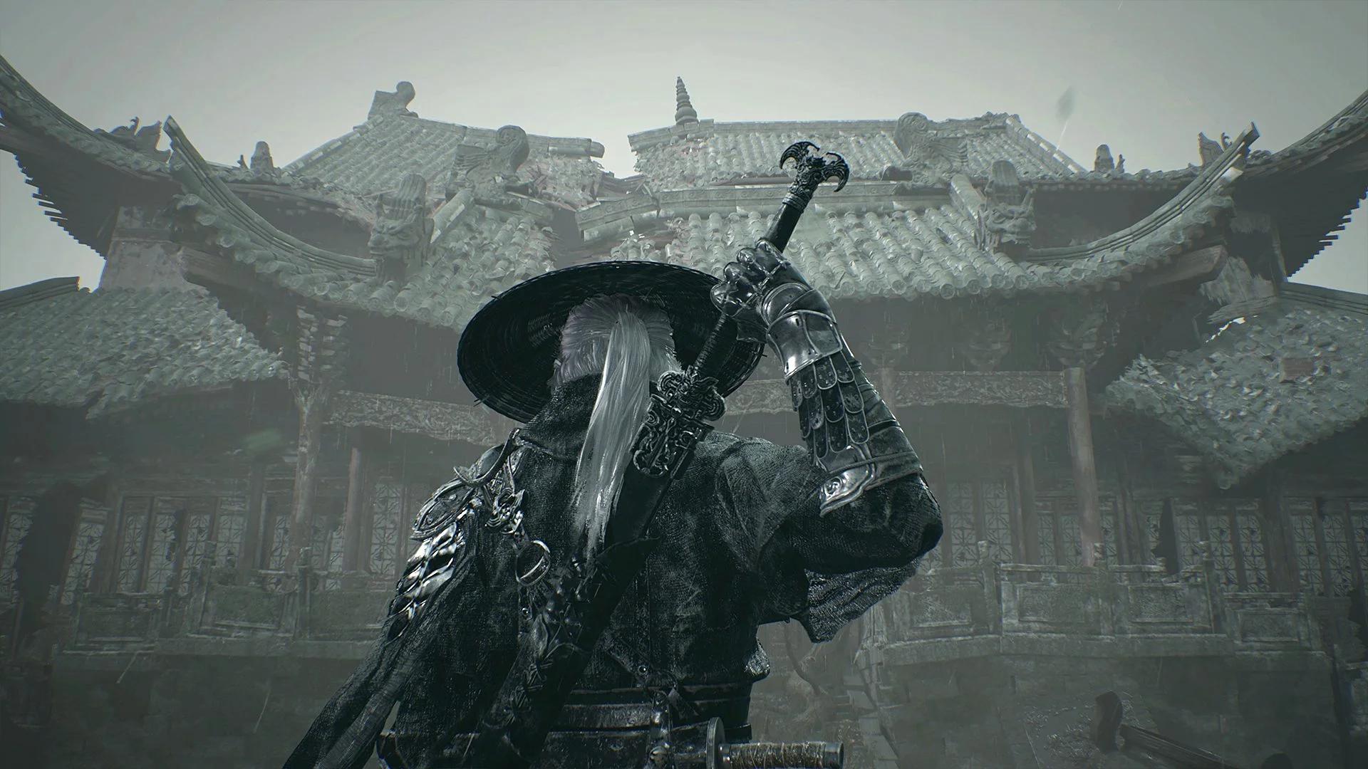 Back view of a warrior in ornate black armor and a wide straw hat standing before a traditional tiled-roof building